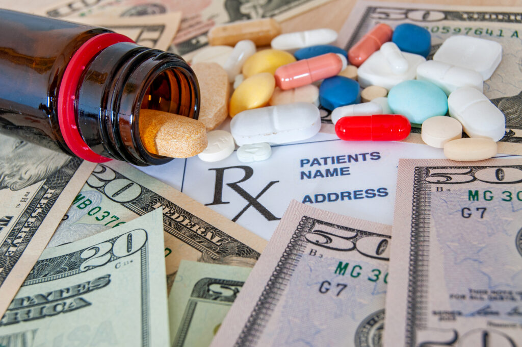 Prescription drugs spilling across bills and money.