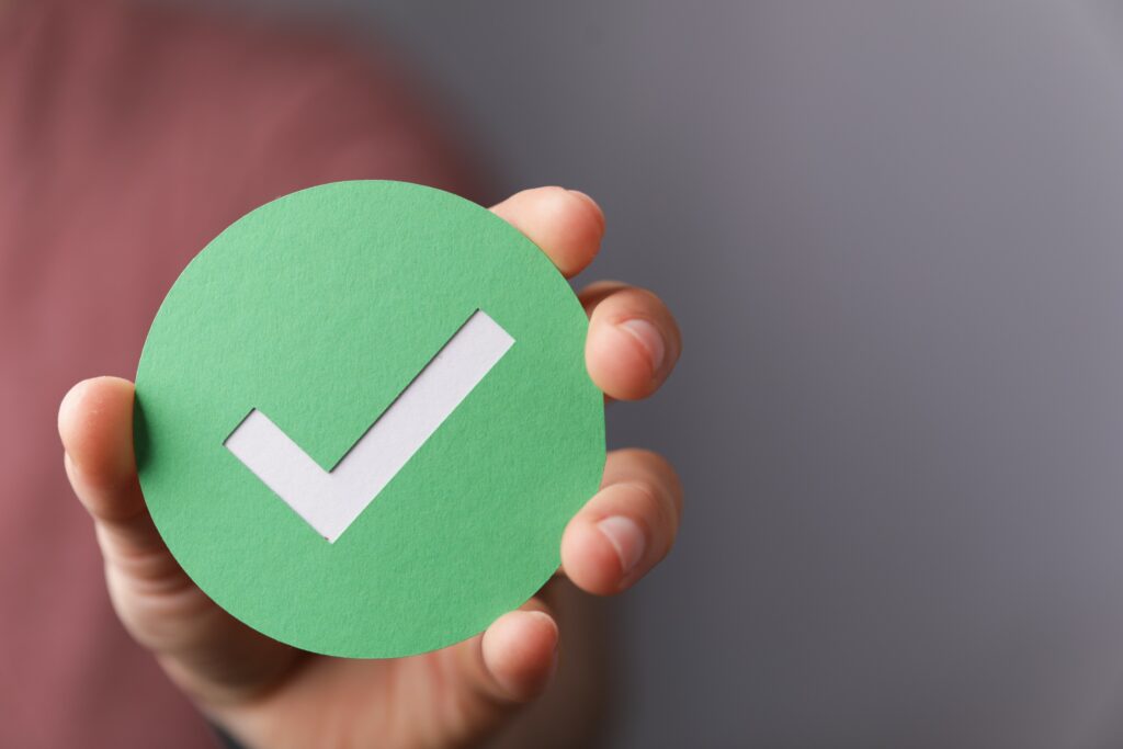 A hand holding a green checkmark